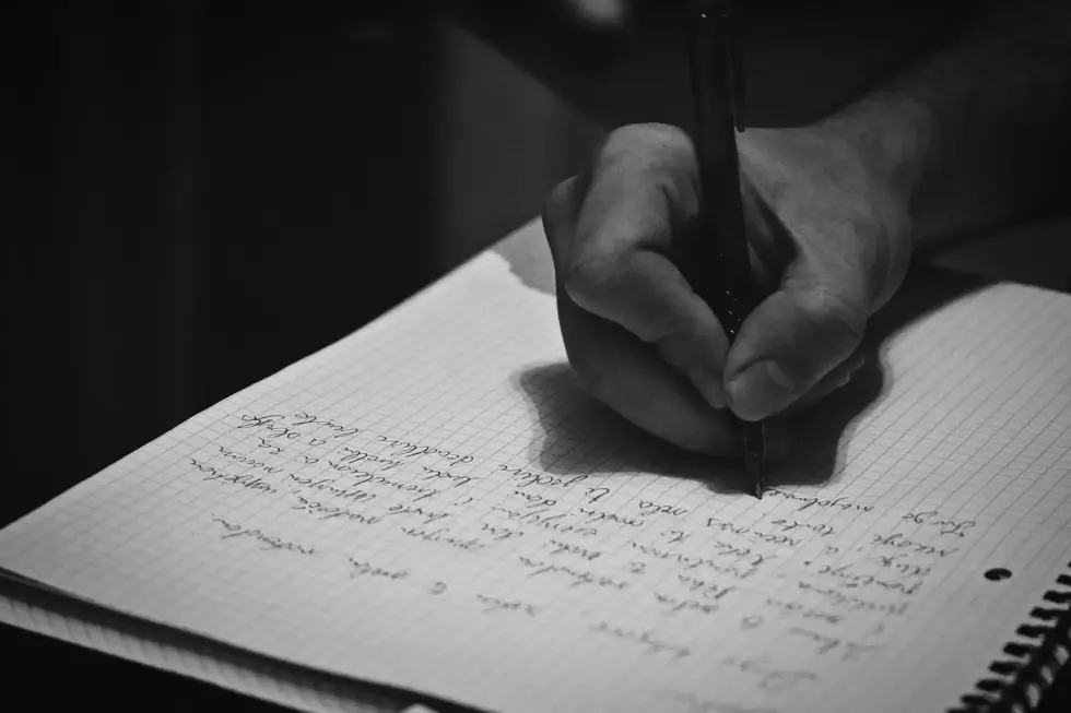 شخص يكتب ملاحظات في دفتر أثناء مراجعة الدروس باستخدام أسلوب الاسترجاع النشط.